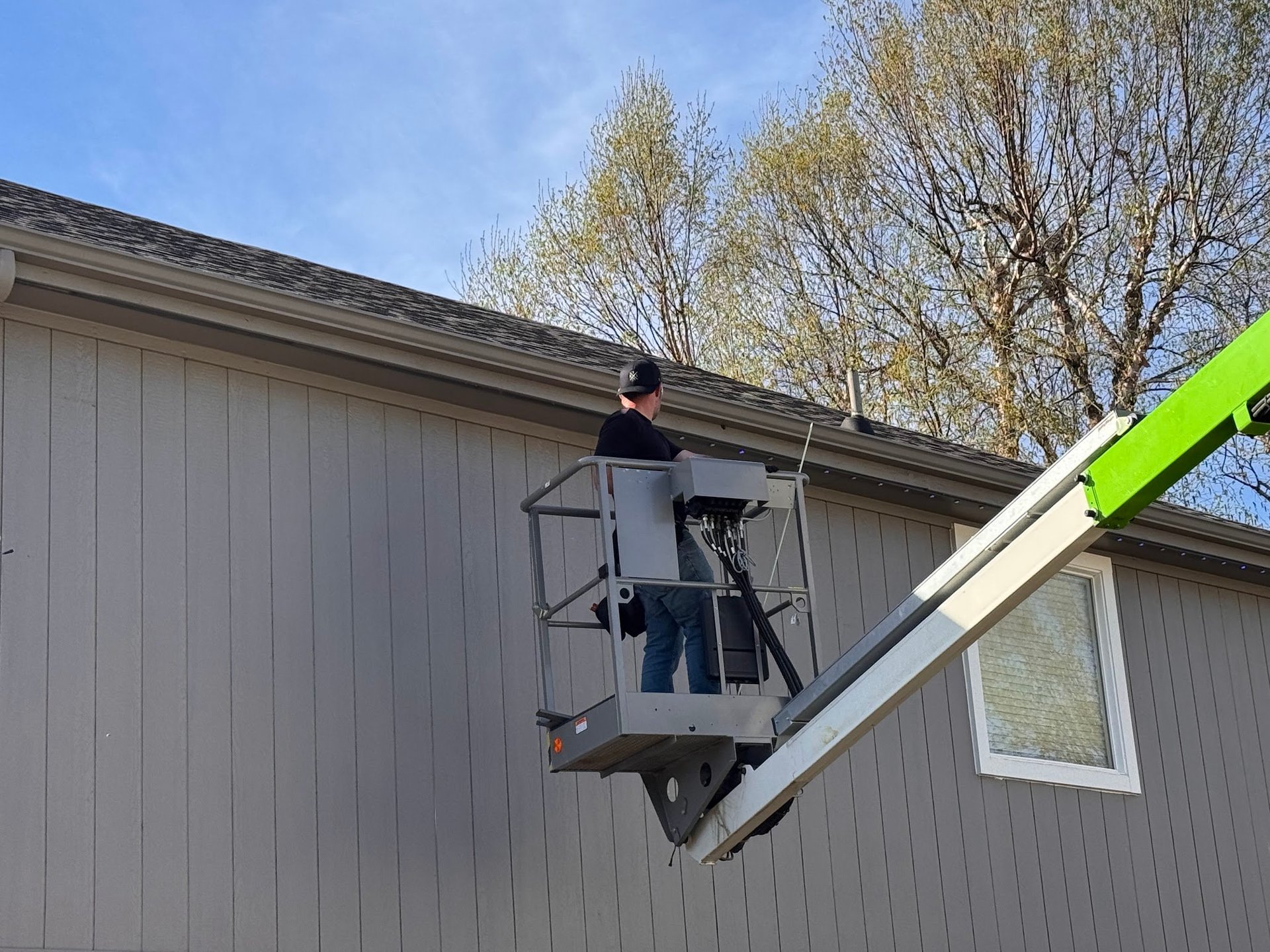 Technician on a lift platform working along a residential roof during installation